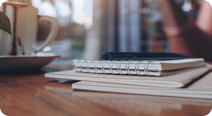 Notebooks and a pen on a wooden desk