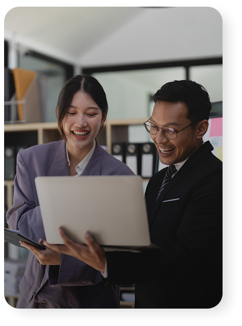 Two business professionals smiling and looking at a laptop.